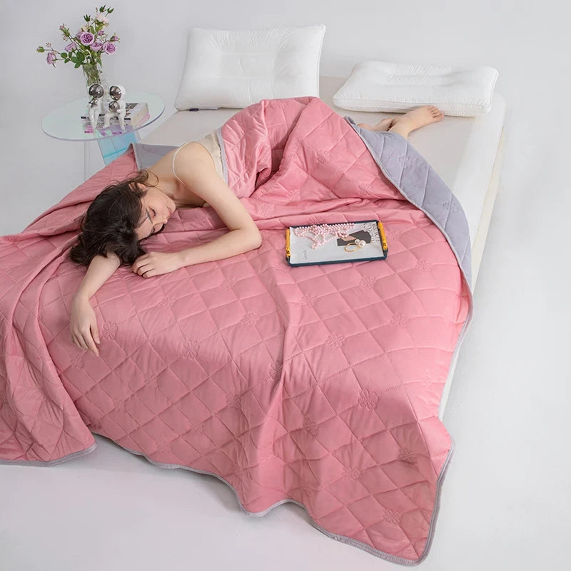 Woman lying on a bed under a pink quilt with a tablet on her chest, in a bedroom setting.