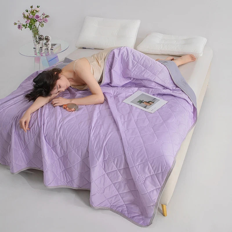 Person lying on a bed under a purple comforter with a minimalistic room setting.
